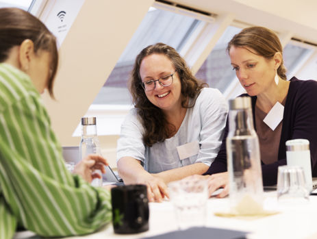 To gymnasielærere samarbejder og griner ved et bord.