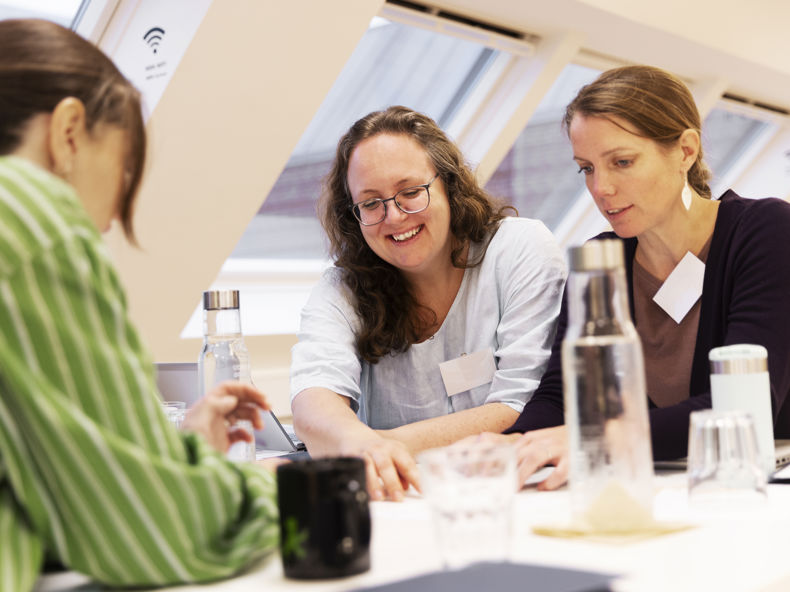 To gymnasielærere samarbejder og griner ved et bord.