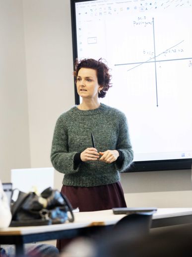 Gymnasielærer underviser klasse foran smartboard.