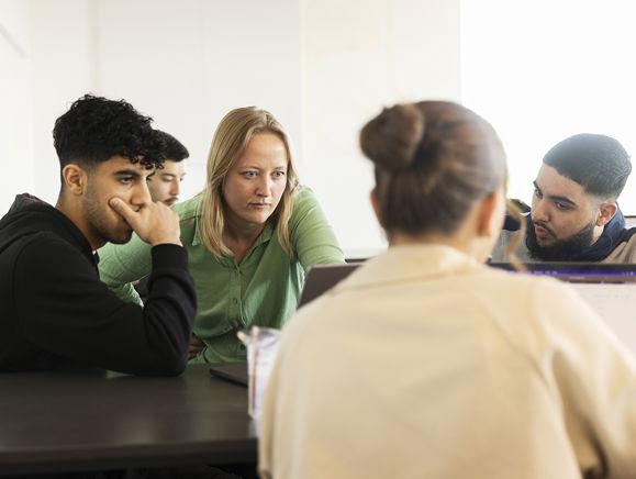 Gymnasielærer hjælper elever med en opgave på en computer