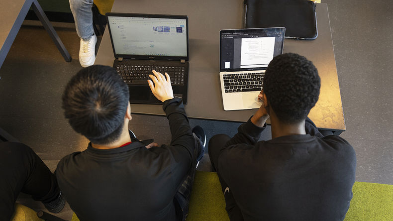 To elever sidder og arbejder på hver deres computer