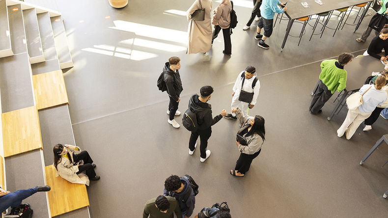 Flere elever står og snakker i skolens fællesområde 