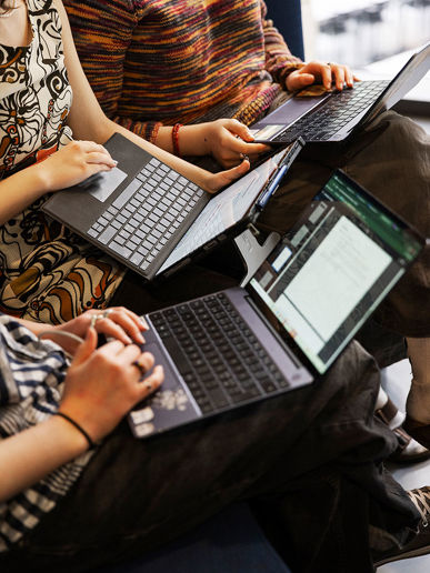 Tre elever sidder tæt sammen og arbejder på computer